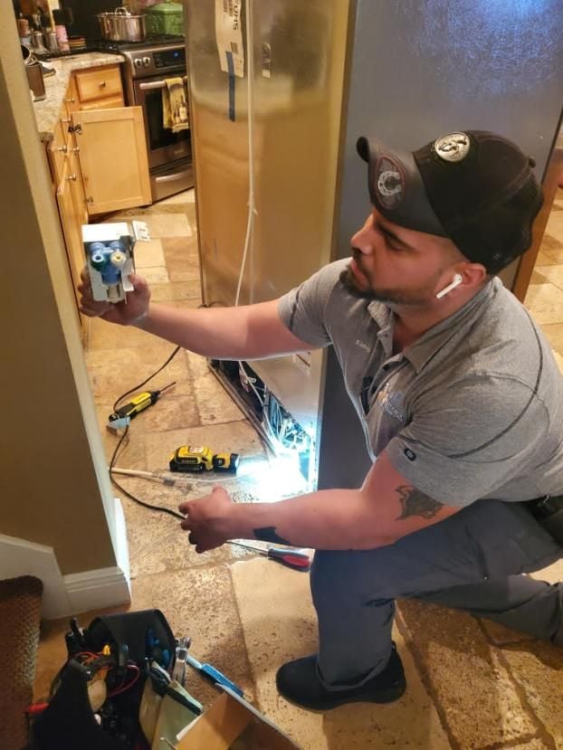 Technician from Elmo's Appliance Repair working on a refrigerator