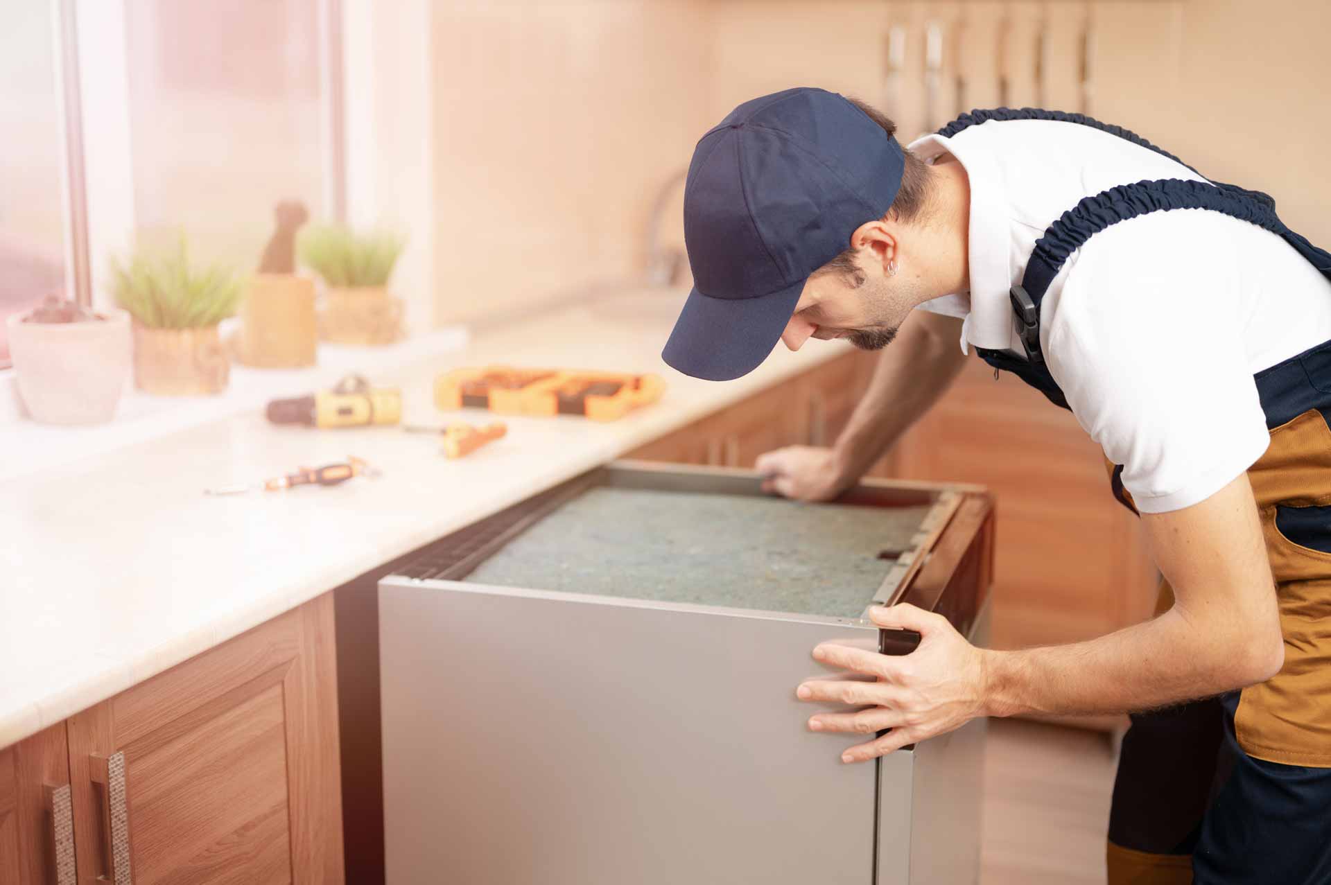 Appliance repair technician pulling a dishwasher out from underneath the kitchen counter for repairs