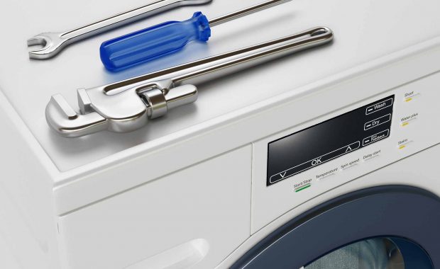 Two wrenches and a screwdriver on top of a washer/dryer